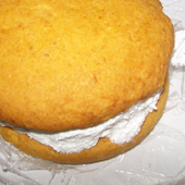 Picture of backed goods, pumpkin whoopie pie with filling.